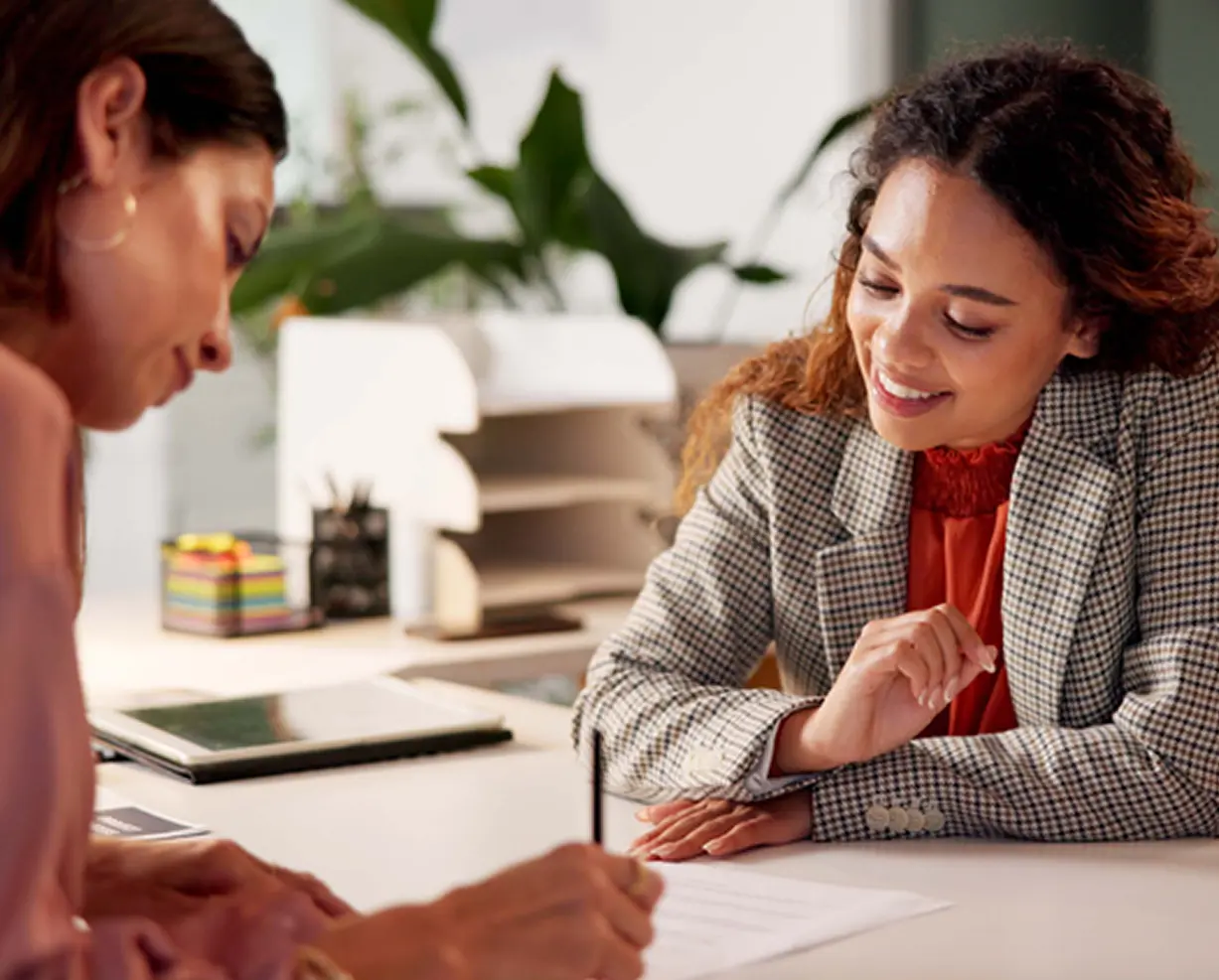 Two women discussing documents in office.