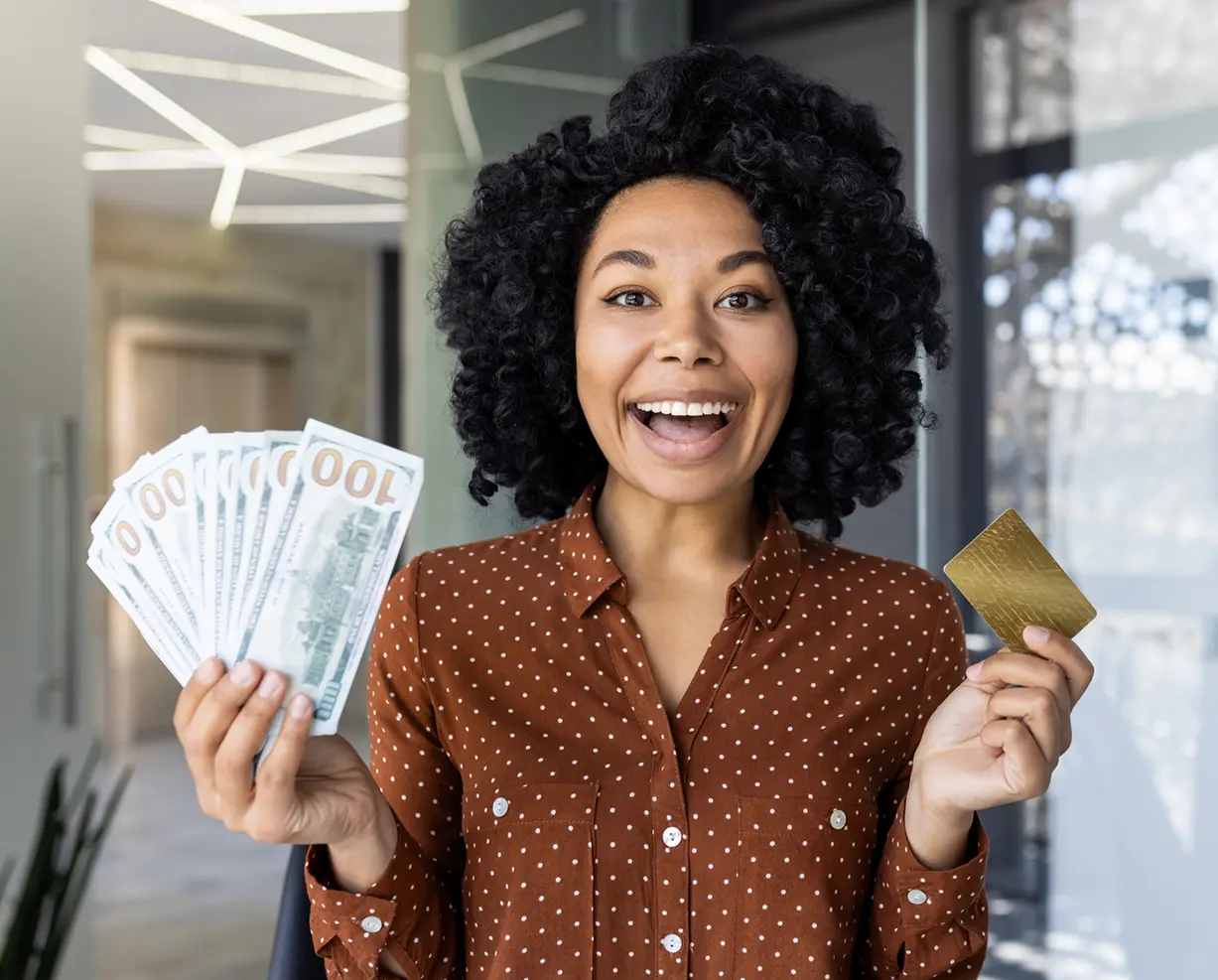 Smiling woman holding cash and credit card.