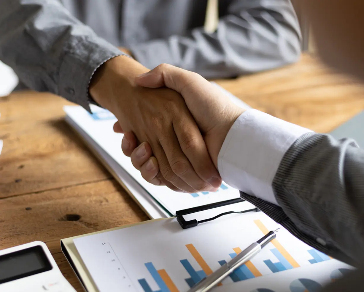 Handshake over business documents on table.
