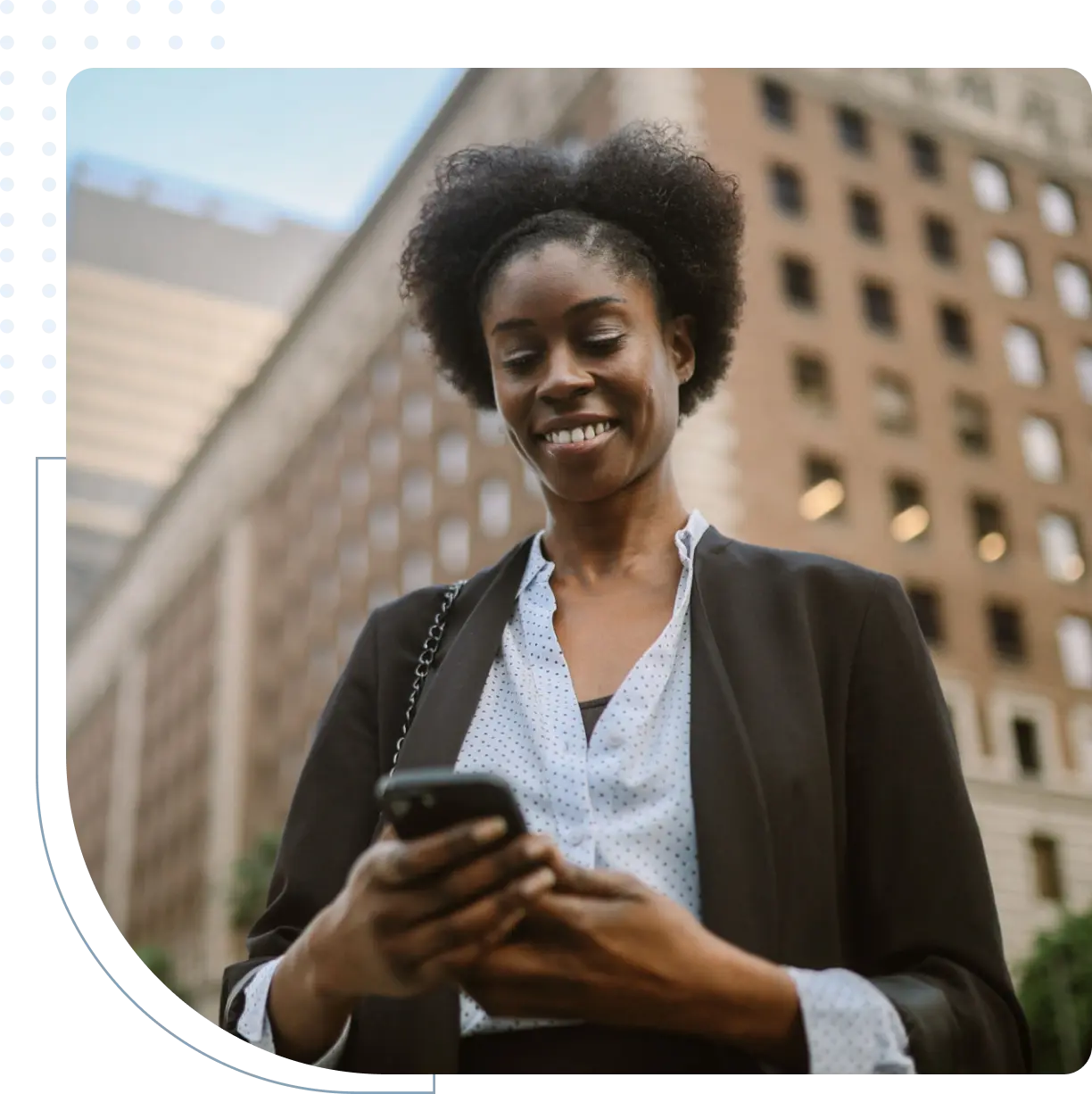 Smiling woman using smartphone in urban setting.
